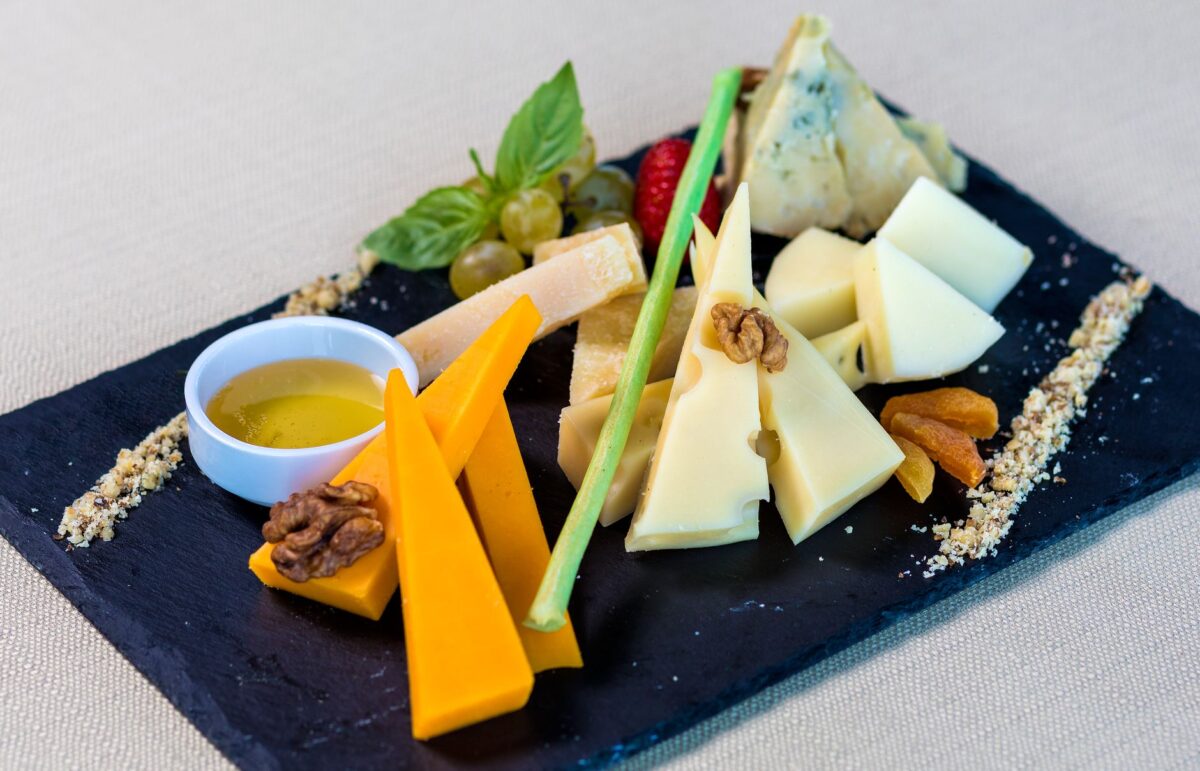 A close-up of an assorted cheese board featuring various cheeses, fruits, and nuts.